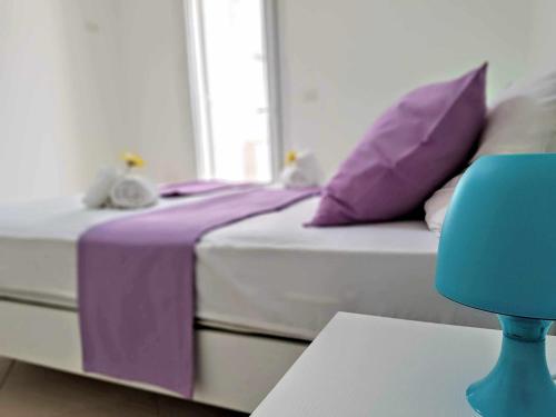 a bed with purple and white pillows and a blue chair at Residence Boccaccio in Torre Pali 