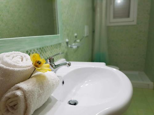 a bathroom with a sink with towels and a yellow flower at Residence Boccaccio in Torre Pali 