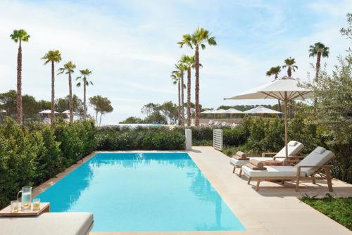 an image of a swimming pool with chairs and an umbrella at Ikos Porto Petro in Portopetro