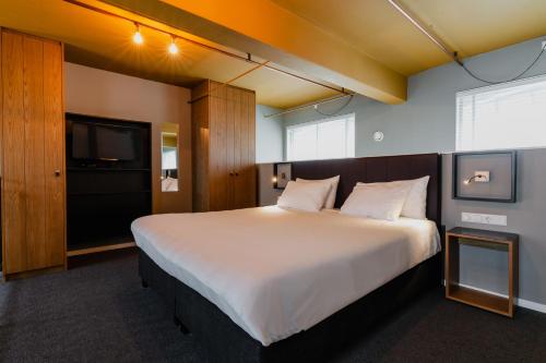 a bedroom with a large bed and a flat screen tv at Apartments De Hallen in Amsterdam