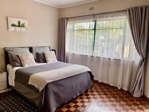 um quarto com uma cama e uma grande janela em Lovely 2 bed apartment with garden - 2047 em Harare