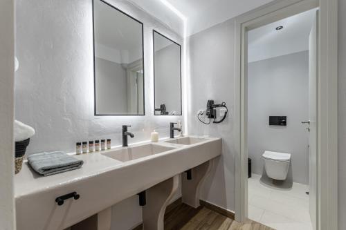 a white bathroom with a sink and a toilet at Heavenly Suites & Studios in Naxos Chora