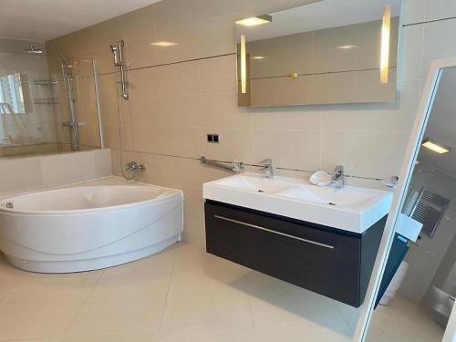 La salle de bains est pourvue d'une baignoire et d'un lavabo. dans l'établissement Penthouse Silver Mountain, Duplex 3 camere - 250 mp luxury garden - Poiana Brasov, à Braşov