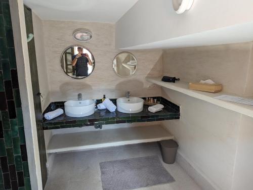 a man taking a picture of a bathroom with two sinks at Dar d'Art in Marrakesh