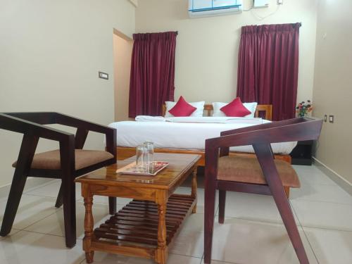 ein Hotelzimmer mit einem Bett, einem Tisch und Stühlen in der Unterkunft Paradise Breeze Inn in Kottakupam