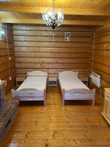 two beds in a wooden room with a chandelier at Chata z góralską duszą in Jabłonka