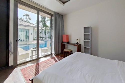 a bedroom with a bed and a view of a pool at Mandala by Villacarte in Bang Tao Beach