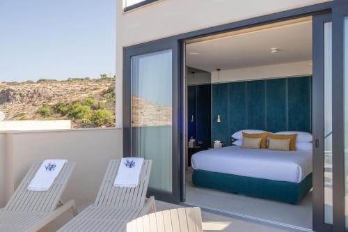 a bedroom with a bed and two chairs on a balcony at Deep Blu Boutique Hotel in Żurrieq
