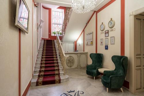 a hallway with a staircase with two green chairs at Metro Hotel Apartments in Odesa