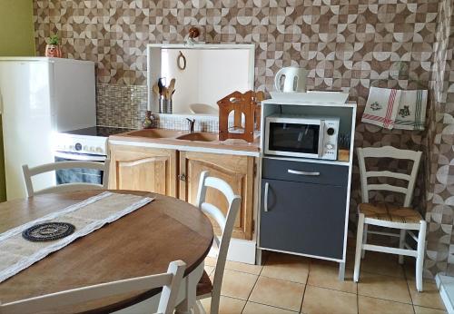 Au nid d'hirondelles في Selles: مطبخ مع طاولة وثلاجة وميكروويف