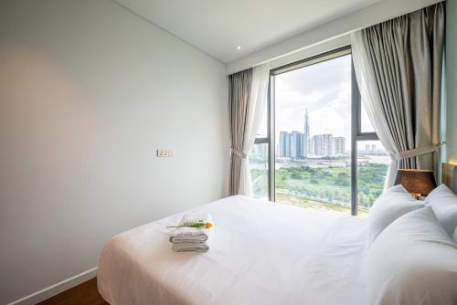a bedroom with a large white bed with a large window at Metropole Thu Thiem Condo Apartment in Ho Chi Minh City