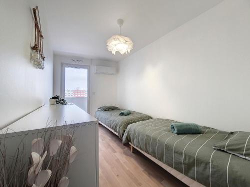 a bedroom with two beds and a chandelier at SAGLIO - Neuf - Parking - Tram - Spa in Strasbourg