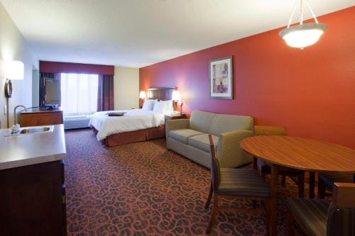 ein Hotelzimmer mit einem Bett, einem Sofa und einem Tisch in der Unterkunft Hampton Inn Minneapolis Northwest Maple Grove in Maple Grove