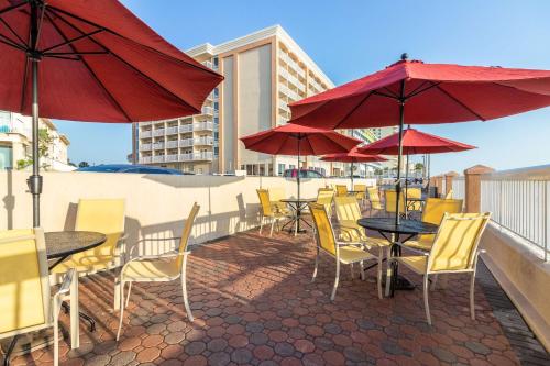 a patio with tables and chairs with red umbrellas at Hampton Inn Daytona Shores-Oceanfront in Daytona Beach