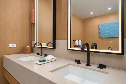 a bathroom with two sinks and two mirrors at Hilton San Diego Gaslamp Quarter in San Diego