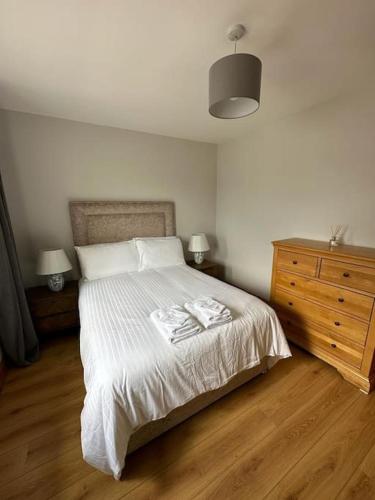 a bedroom with a bed with white sheets and a dresser at Snug apartment centrally located in Galway