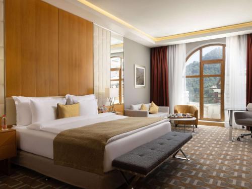 エストサドクにあるRixos Krasnaya Polyana Sochiの大きなベッドと大きな窓が備わるホテルルームです。