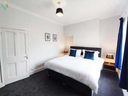 a bedroom with a large white bed with blue pillows at St Bernard House TSAC in Stockton-on-Tees