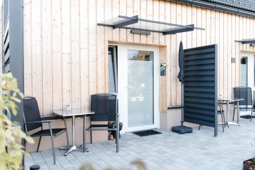 a patio with tables and chairs in front of a building at Pension Blumenwiese - Mitten im Thermenland in Burgau
