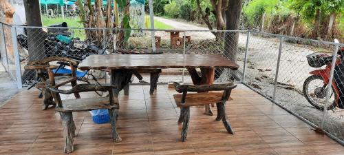 een houten tafel en stoelen op een terras met een hek bij โฮมสเตย์แม่ปราณี2 