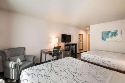 a hotel room with two beds and a desk and a chair at SureStay Plus Hotel by Best Western SeaTac Airport in SeaTac