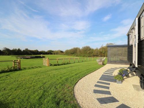 a house with a gravel walkway next to a field at Dragonfly Shepherd's Hut in Aberaeron