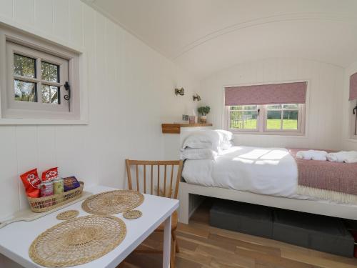 a bedroom with a bed and a table and chairs at Dragonfly Shepherd's Hut in Aberaeron