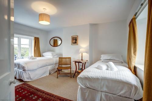 a bedroom with two beds and a table with a chair at Windrush Cottage in Long Hanborough