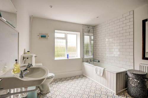 uma casa de banho com uma banheira, um WC e um lavatório. em Windrush Cottage em Long Hanborough
