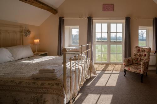 a bedroom with a bed and a chair and windows at Pass the Keys Pheasant Cottage Stunning peaceful home parking in Moreton in Marsh