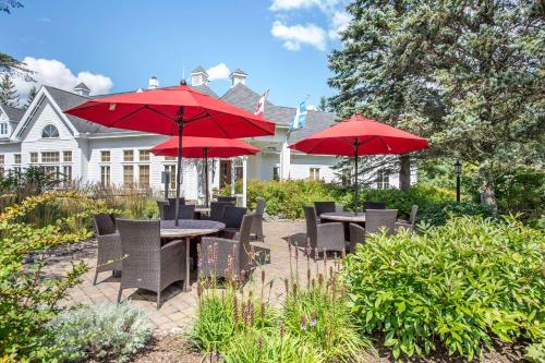 um pátio com mesas e cadeiras com guarda-sóis vermelhos em Hilton Grand Vacations Club Tremblant Canada em Mont-Tremblant