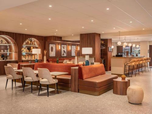a hotel lobby with a couch and tables and chairs at Novotel Orléans Centre Gare in Orléans