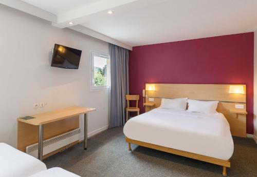 Vals-près-le-PuyにあるB&B HOTEL Le Puy-en-Velayのベッドとデスクが備わるホテルルームです。