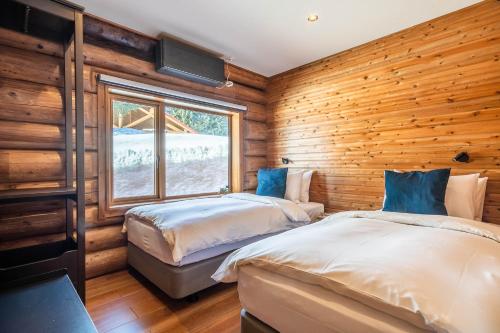 two beds in a room with wooden walls at Villa Rusutsu in Rusutsu