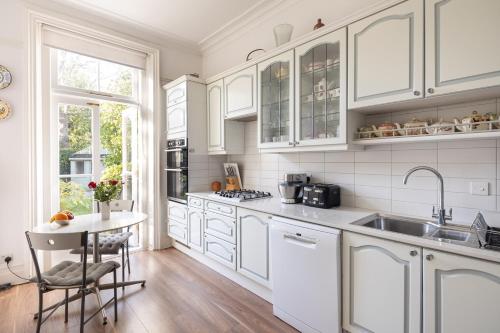 a kitchen with white cabinets and a sink and a table at Veeve - Courtside Charms in London
