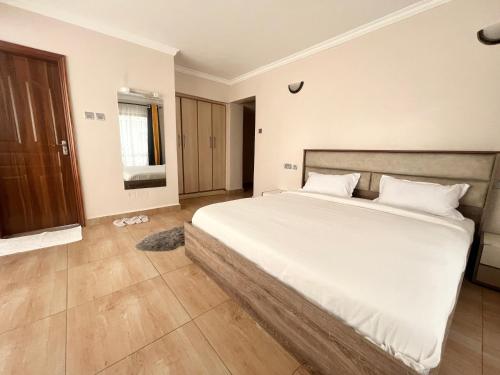 Midtown Executive Suites With Balcony, King Bed في ناكورو: غرفة نوم بسرير كبير مع شراشف بيضاء