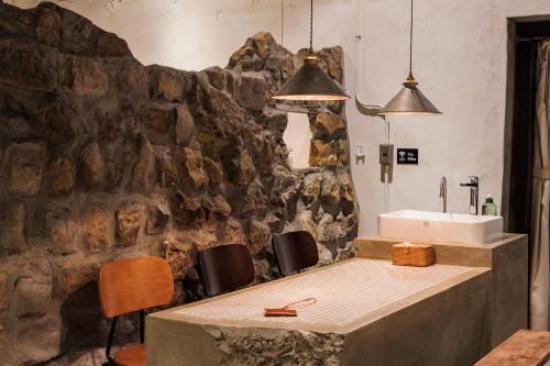 a room with a table and chairs and a stone wall at Yu Apartment in Jiufen