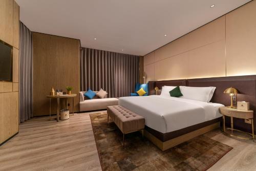 een hotelkamer met een groot bed en een bank bij Echarm Plus Hotel - Foshan Smart New City Zhangcha Metro Station Branch in Foshan