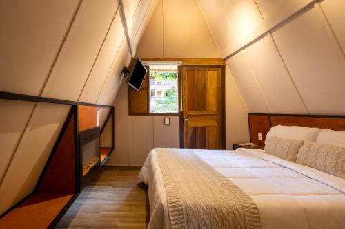 ein Schlafzimmer mit einem großen Bett im Dachgeschoss in der Unterkunft Hotel Fazenda Vilarejo All Inclusive in Conservatória