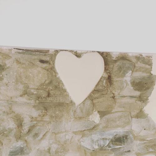 a white heart hanging on a stone wall at Y Boidy Bach in Llangrannog