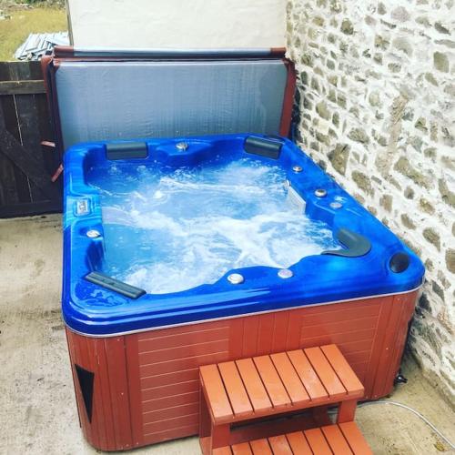 a large hot tub sitting next to a wall at Y Boidy Bach in Llangrannog