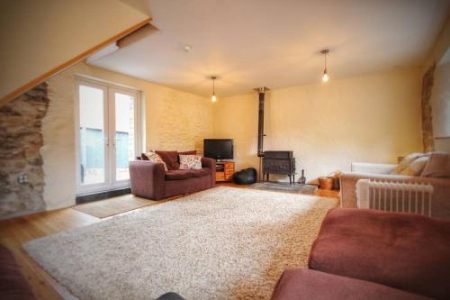 a living room with two couches and a rug at Y Boidy Bach in Llangrannog