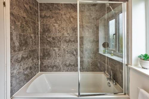 Loughtonにある3 Bedroom Home in Central Milton Keynesのバスルーム(ガラス張りのシャワーブース付きのバスタブ付)が備わります。