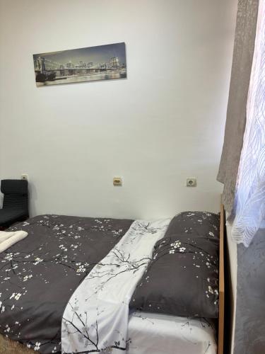 uma cama com lençóis pretos e brancos e uma imagem na parede em Apartman Stil em Kruševac