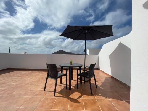 una mesa y sillas en un balcón con sombrilla en Casa volcán, en Tahiche