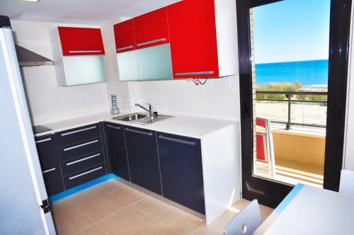 una cocina con armarios rojos y blancos y una ventana en La Salle Litoral - ONLY FAMILIES, en Cambrils