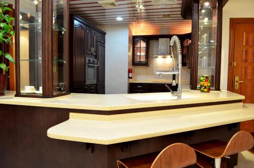 a kitchen with a sink and a counter with chairs at Kiev Tower Hotel Apartments in Manama