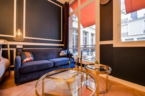 un salon avec un canapé bleu et une table en verre dans l'établissement The Champs Elysées Blue Suite, à Paris
