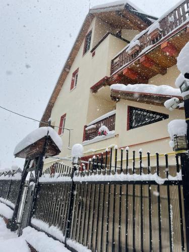 a house with a fence covered in snow at Celesta Trei Brazi in Predeal