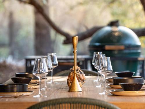 a wooden table with wine glasses on a table at Nomads Den Safari Villas - Heated Pools and Riverbed views in Hoedspruit